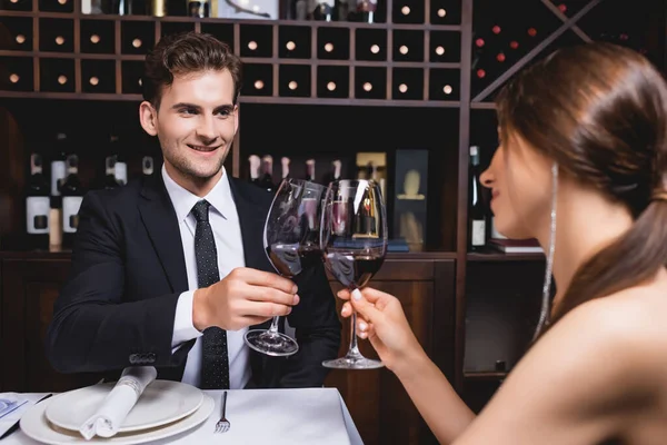 Selective focus of young couple clinking glasses of wine during dating in restaurant — Stock Photo