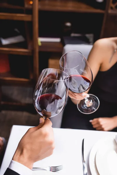 Cropped view of couple toasting with wine during dating in restaurant — Stock Photo