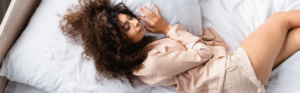 Website header of curly woman with closed eyes lying on bed — Stock Photo