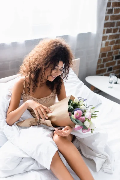 Freudige junge Frau blickt auf Blumen im Bett — Stockfoto