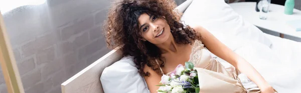 Imagen horizontal de mujer alegre con flores mirando a la cámara - foto de stock