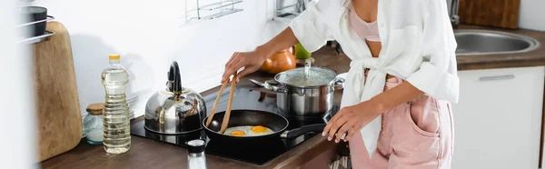 Cultura panorâmica de mulher cozinhando ovos na frigideira na cozinha — Fotografia de Stock