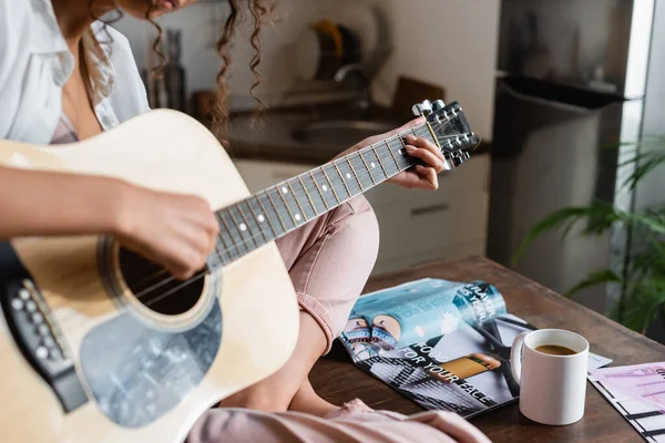Vista recortada de la joven tocando la guitarra acústica en casa - foto de stock