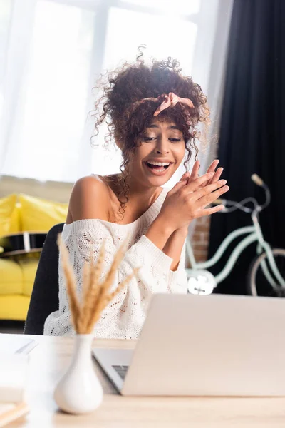 Selective focus of joyful woman laughing near laptop — Stock Photo