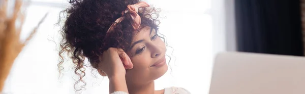 Panoramic crop of pleased and curly woman looking away — Stock Photo