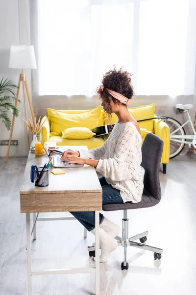 Side view of focused freelancer using laptop while working from hone — Stock Photo