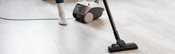 Panoramic crop of woman using vacuum cleaner while cleaning home — Stock Photo