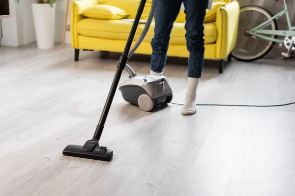 Cropped view of woman in socks using vacuum cleaner while cleaning home — Stock Photo