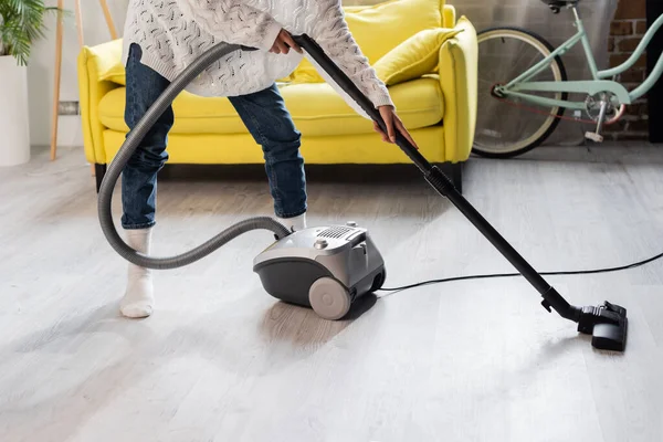 Vue partielle de la femme dans les chaussettes en utilisant l'aspirateur tout en nettoyant la maison — Photo de stock