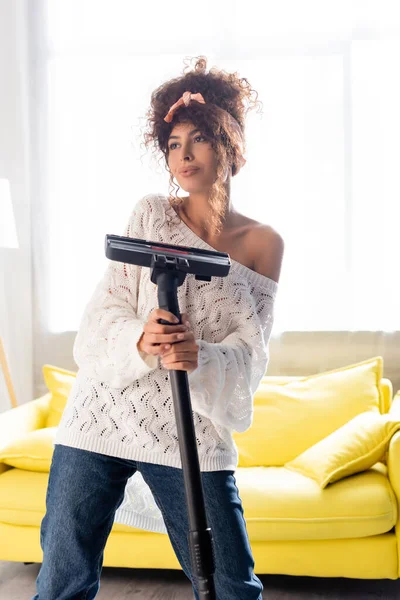 Young woman holding vacuum cleaner and looking away — Stock Photo