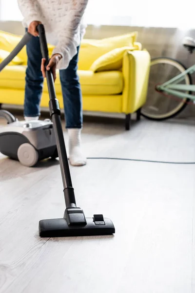 Selective focus of woman in socks using vacuum cleaner while cleaning home — Stock Photo