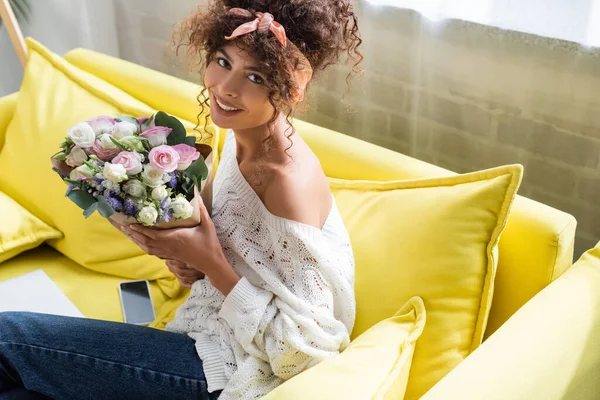 Mujer complacida sosteniendo ramo de flores en sala de estar - foto de stock