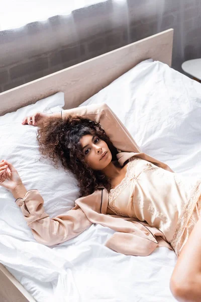 Vue grand angle de bouclé et jeune femme en pyjama couché sur le lit — Photo de stock