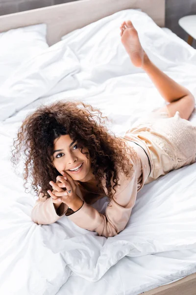 Vista ad alto angolo di riccio e giovane donna in pigiama poggiata sul letto — Foto stock
