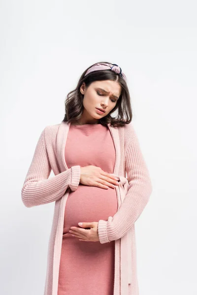 Грустная беременная женщина в повязке касаясь живота изолированы на белом — стоковое фото