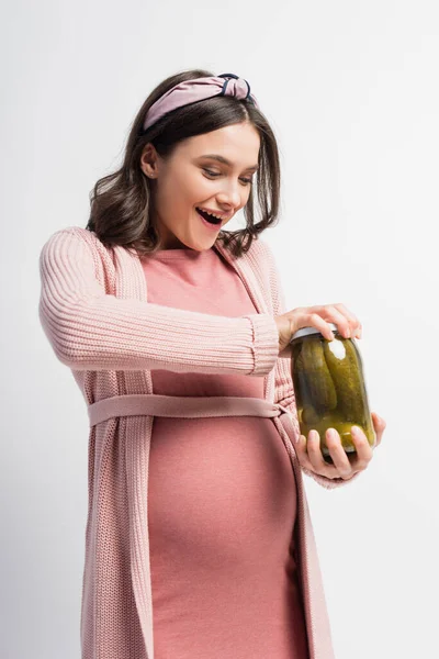 Excited and pregnant woman opening jar with pickled cucumbers isolated on white — Stock Photo