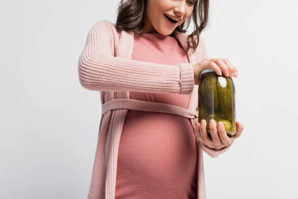 Vista ritagliata di donna eccitata e incinta vaso di apertura con cetrioli sottaceto isolato su bianco — Foto stock