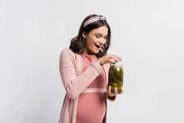 Excited and pregnant woman opening jar with sour and pickled cucumbers isolated on white — Stock Photo