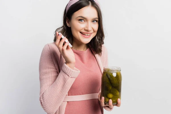 Joyeuse et enceinte femme tenant pot avec des concombres marinés isolés sur blanc — Photo de stock