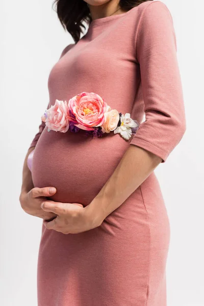 Vista parcial de la mujer embarazada con cinturón floral de pie aislado en blanco - foto de stock