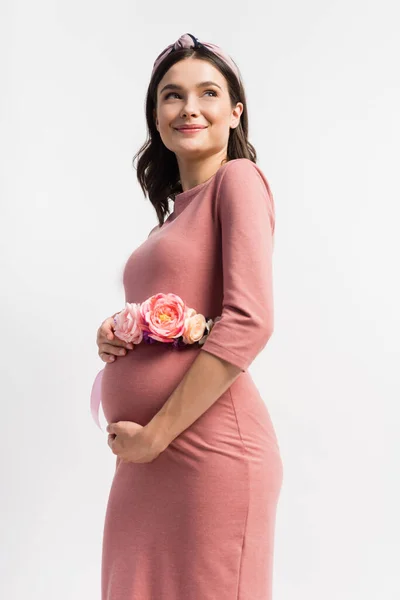 Mujer embarazada complacida con cinturón floral de pie aislado en blanco - foto de stock