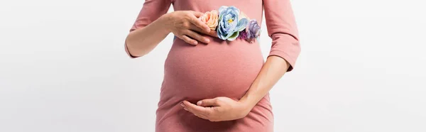 Vista parcial de la mujer embarazada con cinturón floral tocando barriga aislada en blanco, tiro panorámico - foto de stock