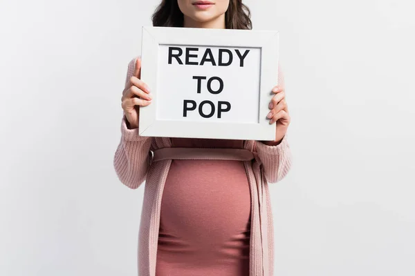 Cropped view of pregnant woman holding board with ready to pop lettering isolated on white — Stock Photo