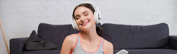 Récolte panoramique de femme heureuse dans les écouteurs sans fil écouter de la musique — Photo de stock