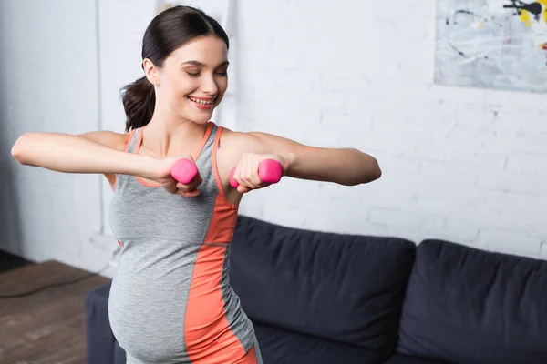 Heureux femme enceinte haltérophilie haltères roses à la maison — Photo de stock