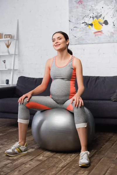 Mulher grávida satisfeito em sportswear exercício no tapete de fitness na sala de estar — Fotografia de Stock