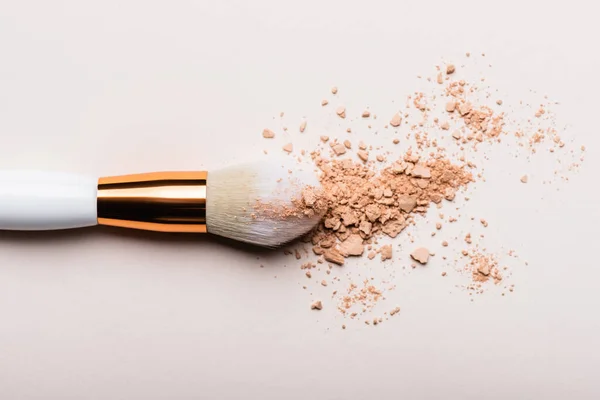 Top view of cosmetic brush with face powder on beige background — Stock Photo