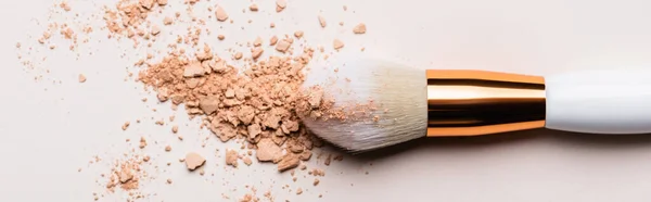 Vista de cerca del cepillo cosmético con polvo facial sobre fondo beige, plano panorámico - foto de stock