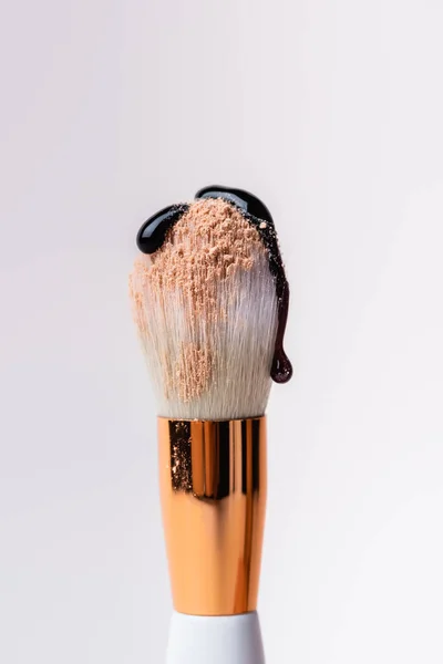 Close up view of cosmetic brush with face powder and dripping black liquid isolated on white — Stock Photo