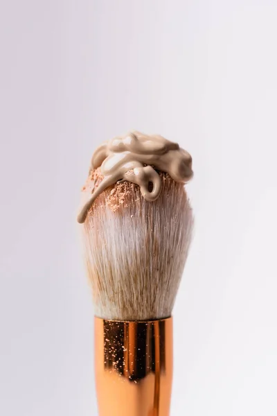Vista de cerca del cepillo cosmético con polvo facial y base aislada en blanco - foto de stock