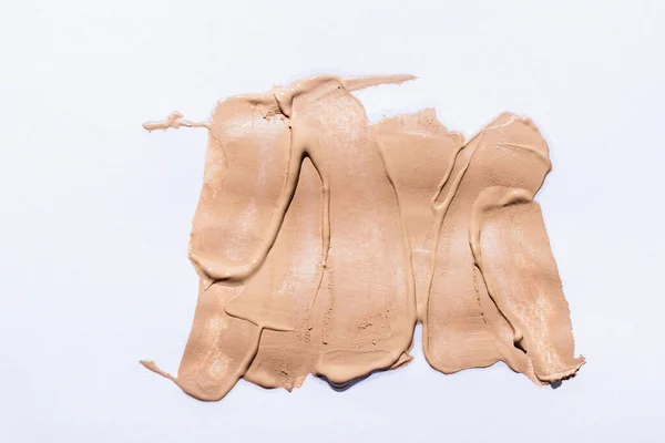 Draufsicht auf beige face foundation Pinselstriche auf weißem Hintergrund — Stockfoto