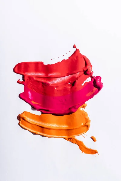 Vue de dessus des coups de pinceau abstraits rouge, orange et rose sur fond blanc — Photo de stock