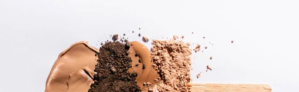 Vista superior de la base de la cara beige pinceladas y polvo de sombra de ojos con palo de madera sobre fondo blanco, plano panorámico — Stock Photo