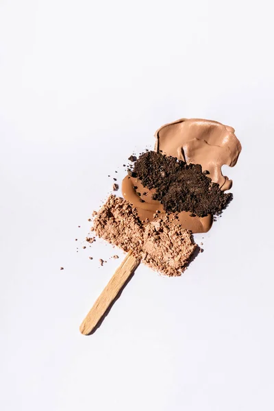 Вид зверху бежевого лицьового фундаменту пензлики та порошок для повік з дерев'яною палицею на білому тлі — стокове фото