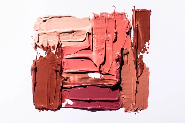Top view of pink, beige and brown abstract brushstrokes of lipstick isolated on white — Stock Photo