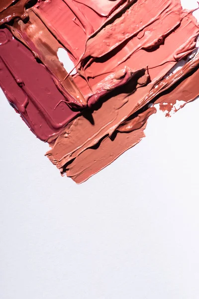 Vue de dessus des coups de pinceau abstraits rose, beige et marron de rouge à lèvres isolés sur blanc — Photo de stock