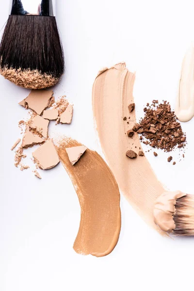 Top view of cosmetic brushes with face foundation brushstrokes and powder on white — Stock Photo