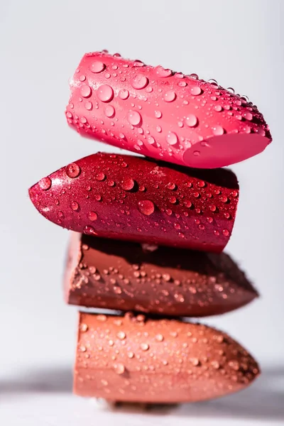 Vista de cerca de lápices labiales de colores húmedos sobre fondo blanco - foto de stock