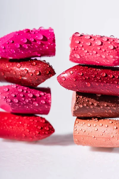 Vista de cerca de lápices labiales de colores húmedos sobre fondo blanco - foto de stock