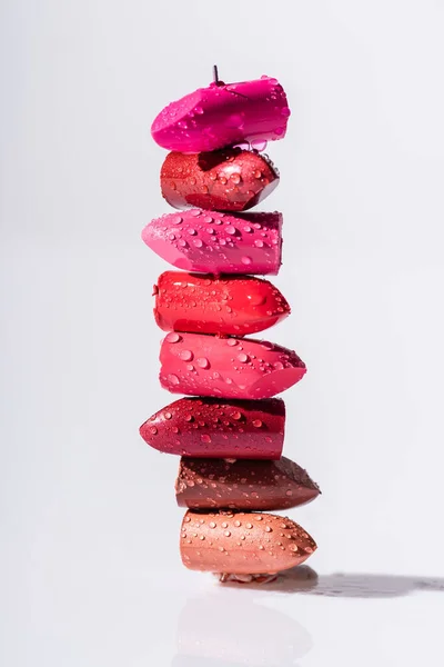 Stack of wet colorful lipsticks on white background — Stock Photo