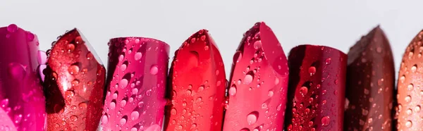 Close up view of wet lipsticks in row isolated on white, panoramic shot — Stock Photo