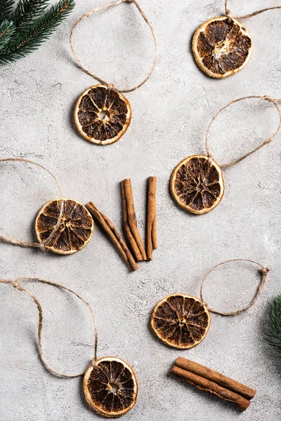 Top view of dried orange pieces with strings, cinnamon sticks and pine branches — Stock Photo