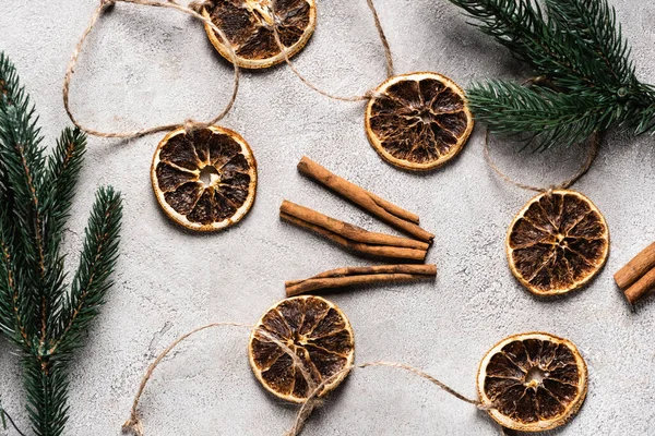 Vista superior de piezas de naranja secas con varillas de canela sobre fondo gris - foto de stock