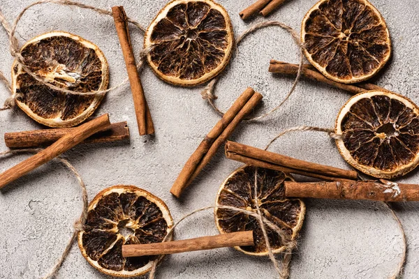 Vista superior de pedaços de laranja seca e paus de canela no fundo cinza — Fotografia de Stock