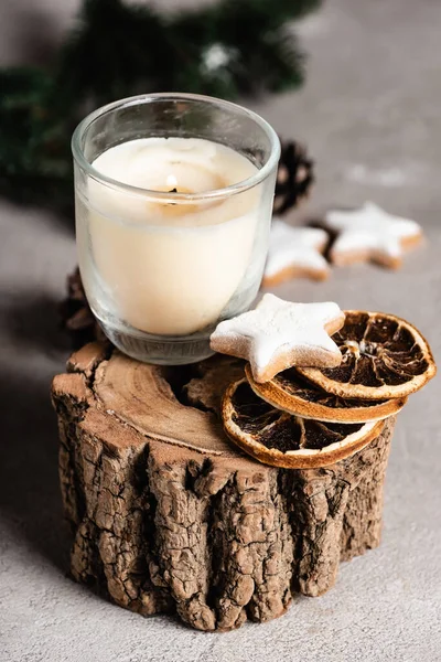 Enfoque selectivo de vela con rodajas de naranja secas y galleta en soporte de madera - foto de stock