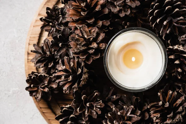 Top view of scented candle with pine cones on wooden plate — Stock Photo